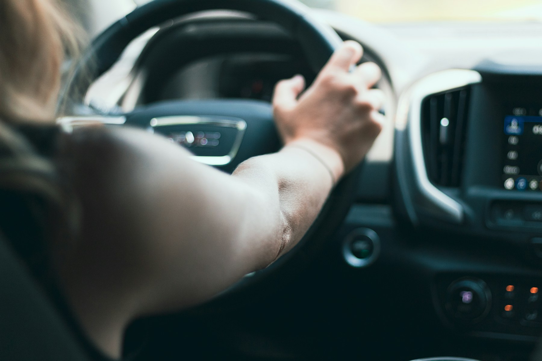 Vue illustrative d’une main au volant d’une voiture, éclairée par la lumière du jour